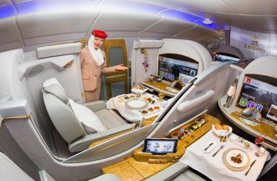First-Class Emirates eine Flugbegleiterin weißt zum Sitzplatz mit eigenem TV